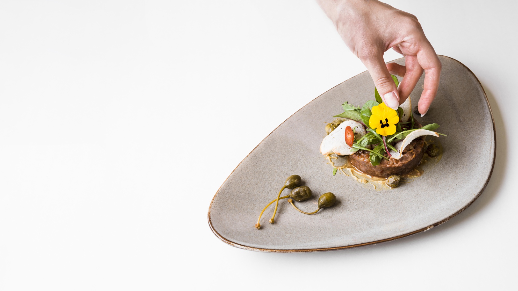 Close-up hands plating a composed dish