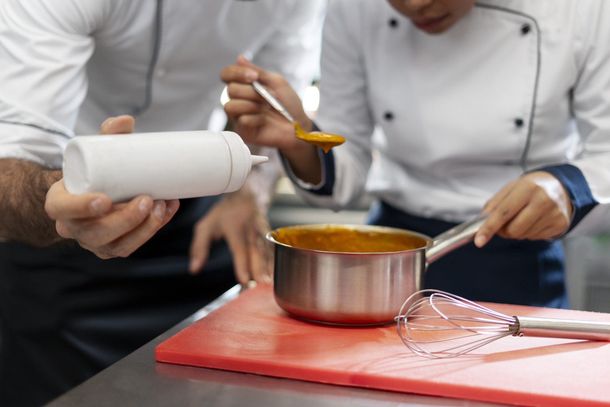 Chef demonstrating sauce technique to a small class